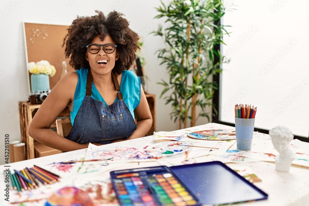Fototapeta premium Beautiful african american woman with afro hair painting at art studio with hand on stomach because nausea, painful disease feeling unwell. ache concept.