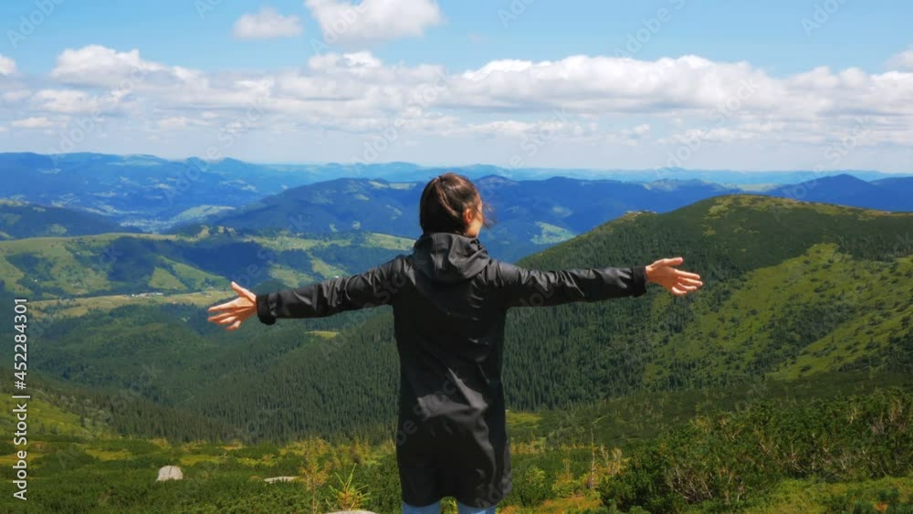 A young woman traveler stands on the top of the cliff and looks at the mountain landscape. A young attractive woman traveler stands on the top of the mountain and looks into the distance at the A young woman traveler stands on the top of the cliff and looks at the mountain landscape. A young attractive woman traveler stands on the top of the mountain and looks into the distance at the