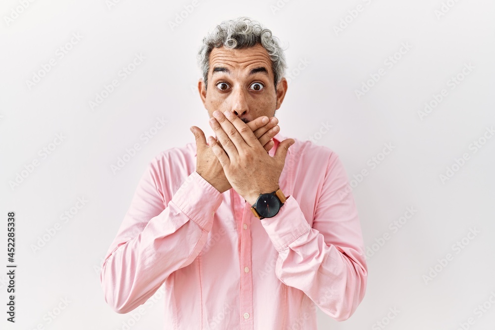 Middle age hispanic man standing over isolated background shocked covering mouth with hands for mistake. secret concept.
