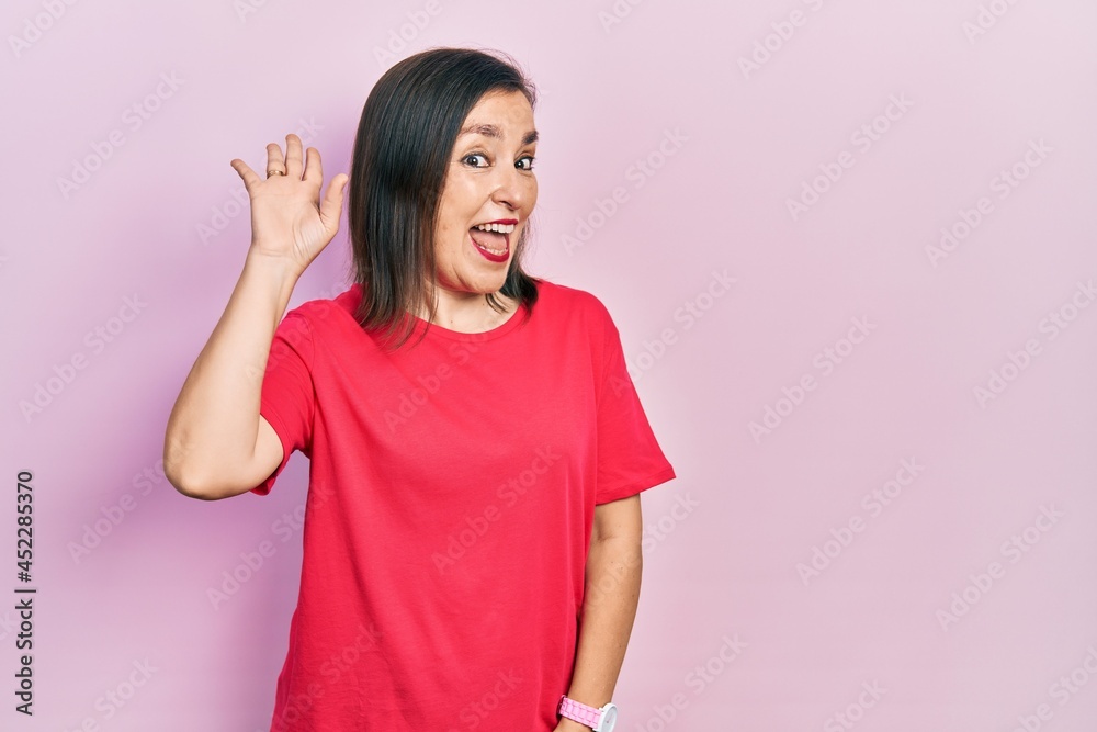 Middle age hispanic woman wearing casual clothes waiving saying hello happy and smiling, friendly welcome gesture Middle age hispanic woman wearing casual clothes waiving saying hello happy and smiling, friendly welcome gesture
