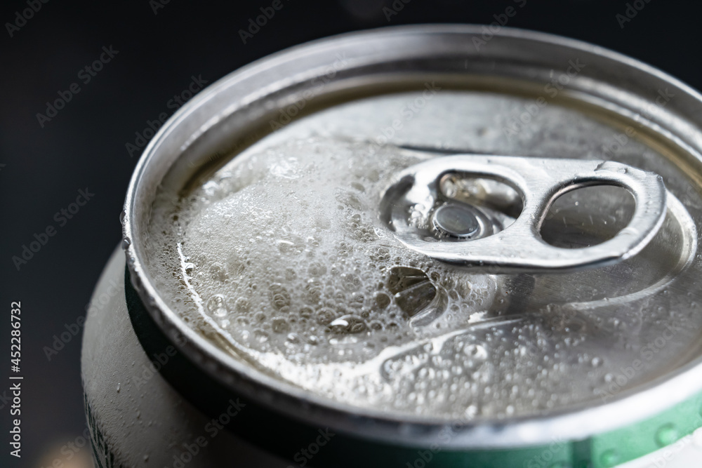 the foam rises up from the open tin beer can. close-up. the foam rises up from the open tin beer can. close-up.