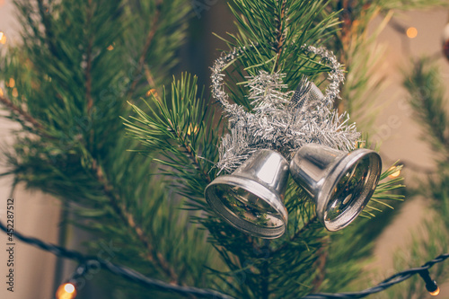 Christmas bells and fir-tree branch on gray background.