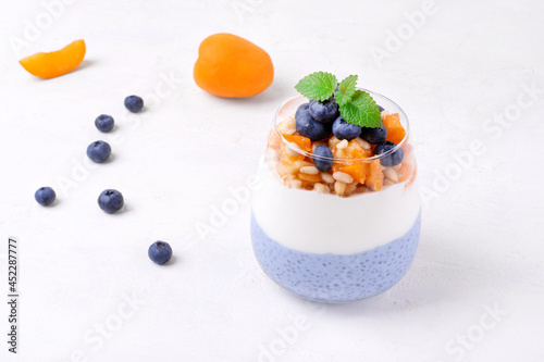 Chia pudding with blue matcha  yogurt  blueberry  apricot  banana and pine nuts. Healthy layered dessert