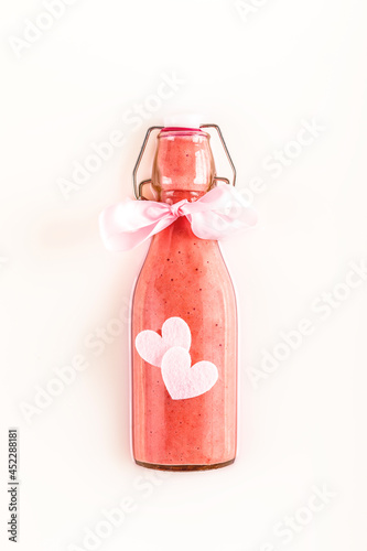 Glass bottle with refreshing pink strawberry smoothie over milk with lovely hearts. Healthy, detox and diet food concept. Present