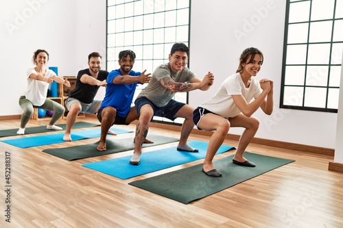 Group of young sporty people smiling happy training yoga at sport center.