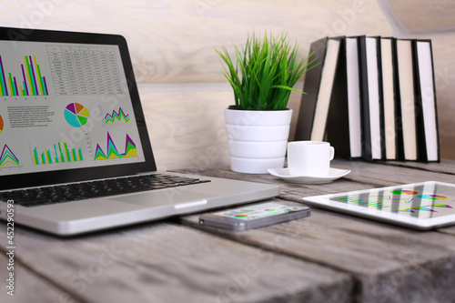 PC, laptop, tablet and phone financial statistics displayed on the screen on wooden table.