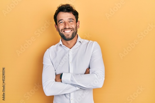 Handsome man with beard wearing casual white t shirt happy face smiling with crossed arms looking at the camera. positive person.