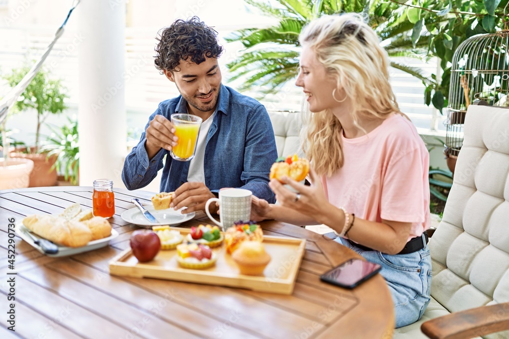Young couple smiling happy having breakfast sitting on the table at terrace. Young couple smiling happy having breakfast sitting on the table at terrace.