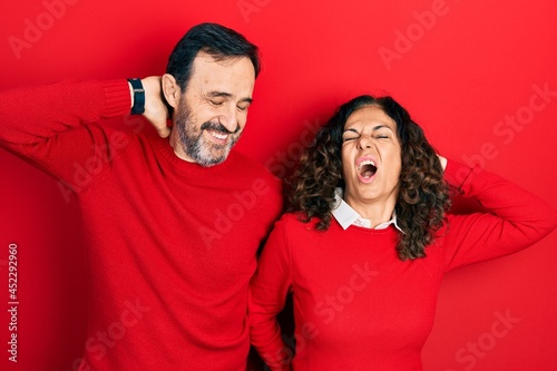 Middle age couple of hispanic woman and man hugging and standing together suffering of neck ache injury, touching neck with hand, muscular pain © Krakenimages.com