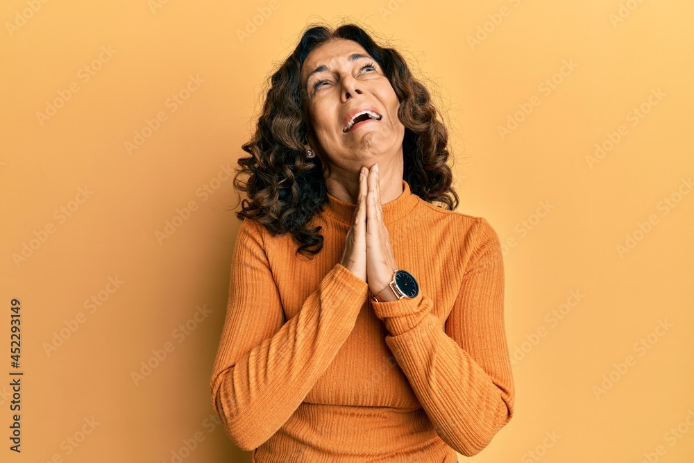 Middle age hispanic woman wearing casual clothes begging and praying with hands together with hope expression on face very emotional and worried. begging. Middle age hispanic woman wearing casual clothes begging and praying with hands together with hope expression on face very emotional and worried. begging.