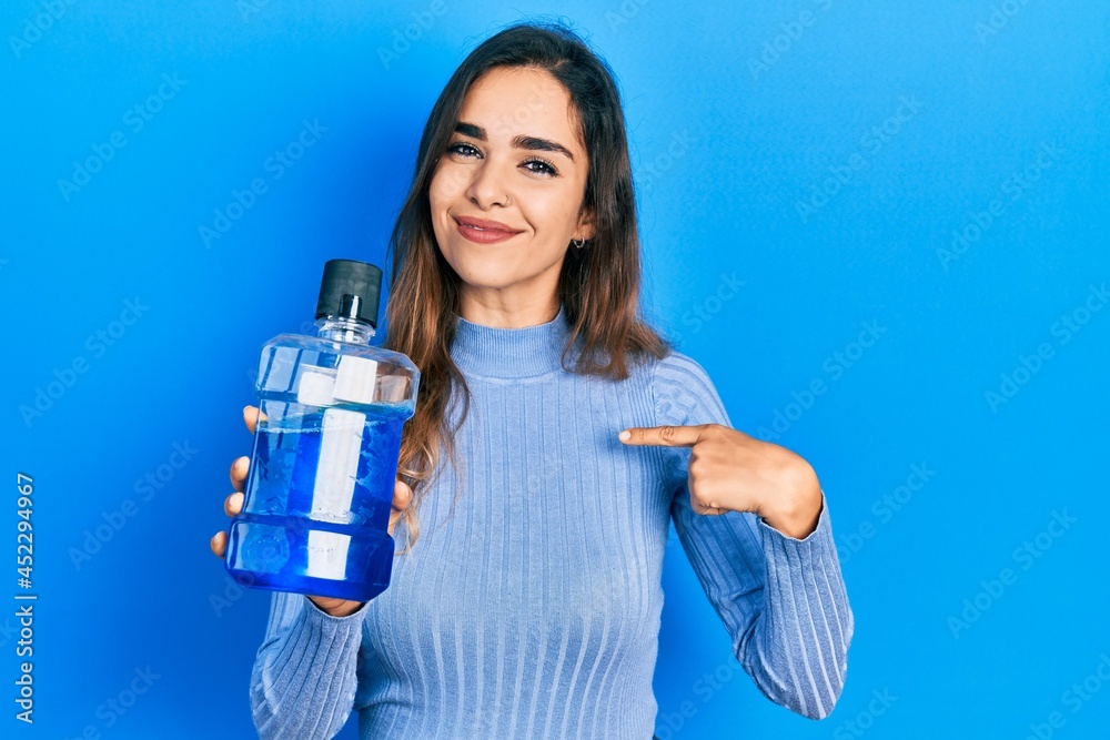 Young hispanic girl holding mouthwash for fresh breath pointing finger to one self smiling happy and proud - obrazy, fototapety, plakaty 