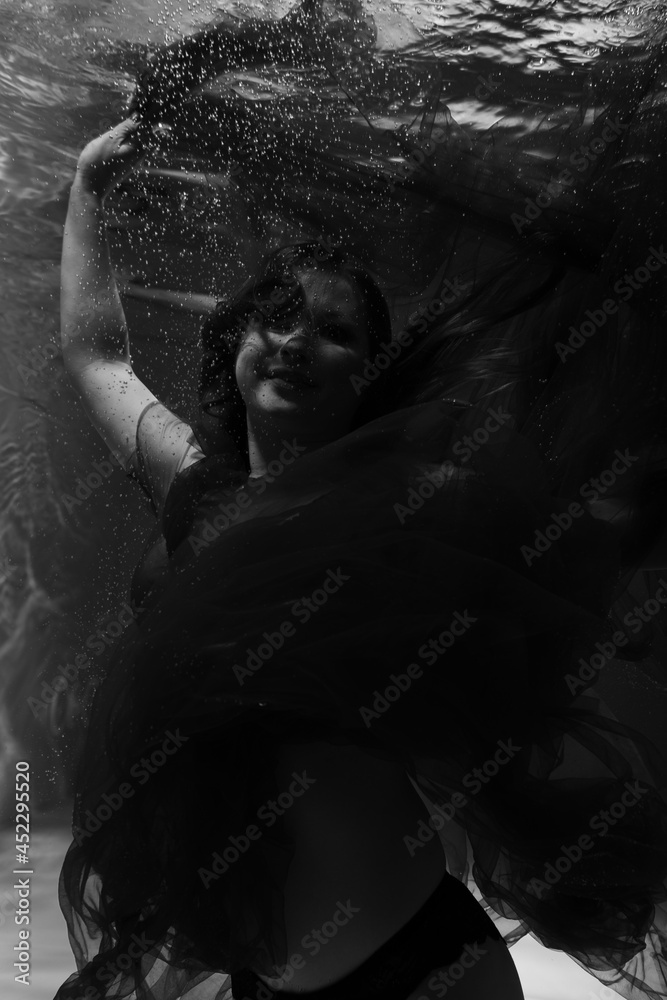 Beautiful girl underwater in the pool. Black and white photography, creative and mystical Beautiful girl underwater in the pool. Black and white photography, creative and mystical