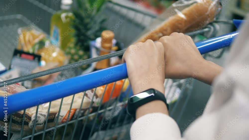 Shopping cart is being pulled by a buyer's hands Shopping cart is being pulled by a buyer's hands