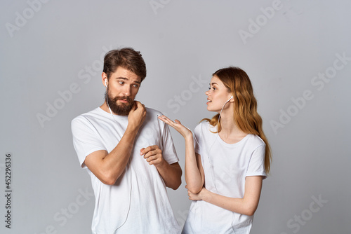 young couple in headphones listening to music entertainment together on light background