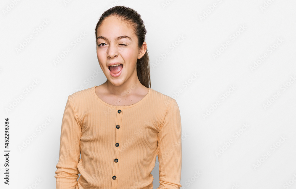 Beautiful brunette little girl wearing casual sweater winking looking at the camera with sexy expression, cheerful and happy face. Beautiful brunette little girl wearing casual sweater winking looking at the camera with sexy expression, cheerful and happy face.