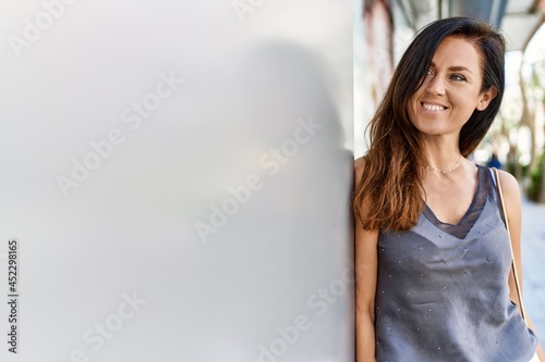 Beautiful caucasian woman looking elegant and happy leaning on a wall outdoors on a sunny day