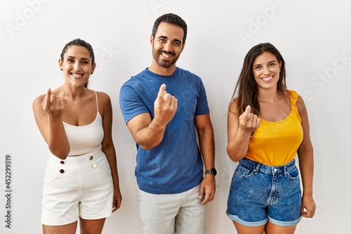Group of young hispanic people standing over isolated background beckoning come here gesture with hand inviting welcoming happy and smiling