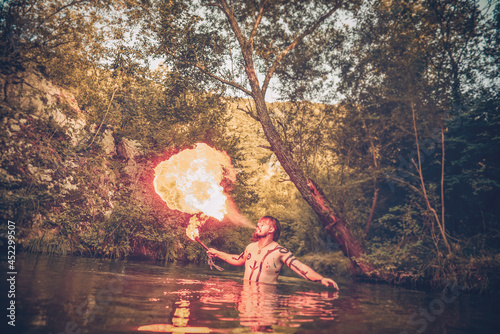 Man in a river blowing fire