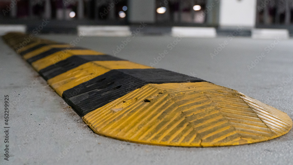 Traffic safety speed bump on an asphalt road in a parking area. Speed bumps (or speed breakers