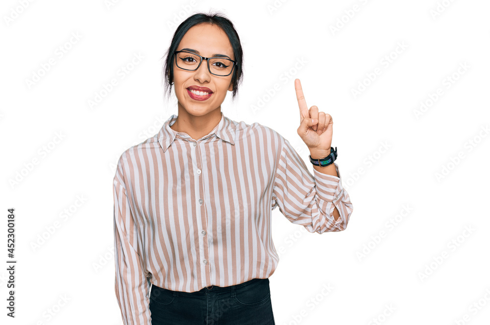 Young hispanic girl wearing casual clothes and glasses pointing finger up with successful idea. exited and happy. number one. Young hispanic girl wearing casual clothes and glasses pointing finger up with successful idea. exited and happy. number one.