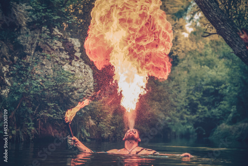 Man in a river blowing fire
