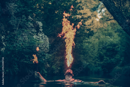 Man in a river blowing fire