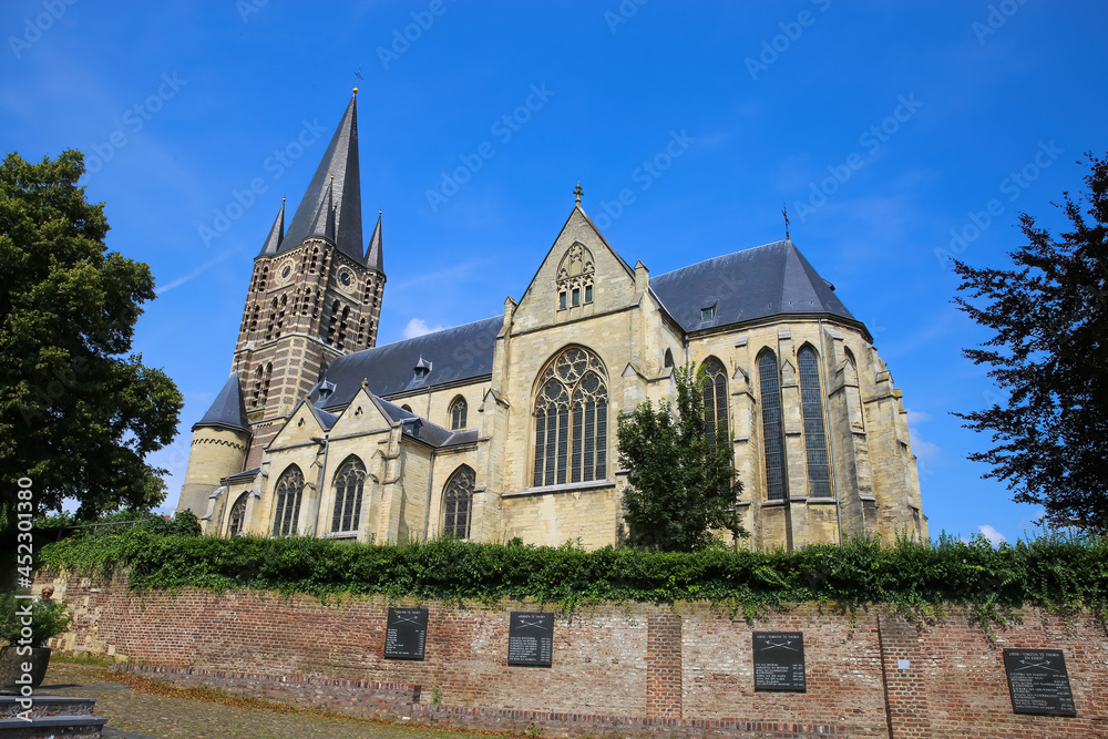 Thorn (Limburg), Netherlands - July 9. 2021: View on roman abbey church with trees against blus summer sky