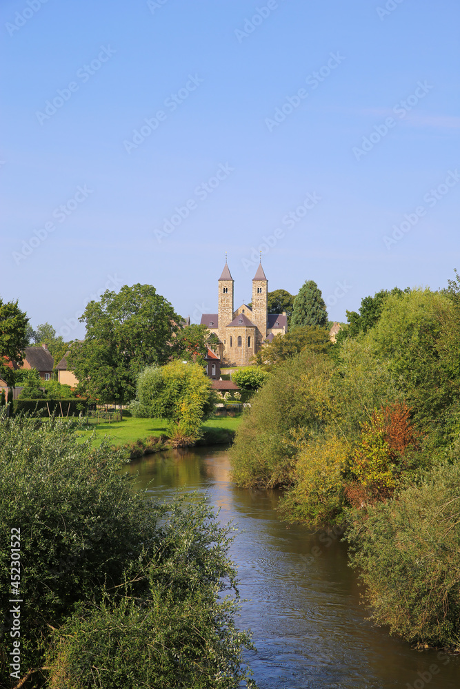 View over small river Roer with green trees on roman catholic basilica with monastery  from 11th century against blue summer sky - Sint Odilienberg (near Roermond) - Netherlands