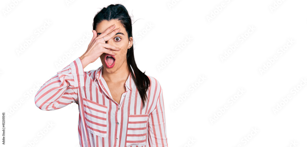 Young hispanic woman wearing casual clothes peeking in shock covering face and eyes with hand, looking through fingers afraid Young hispanic woman wearing casual clothes peeking in shock covering face and eyes with hand, looking through fingers afraid