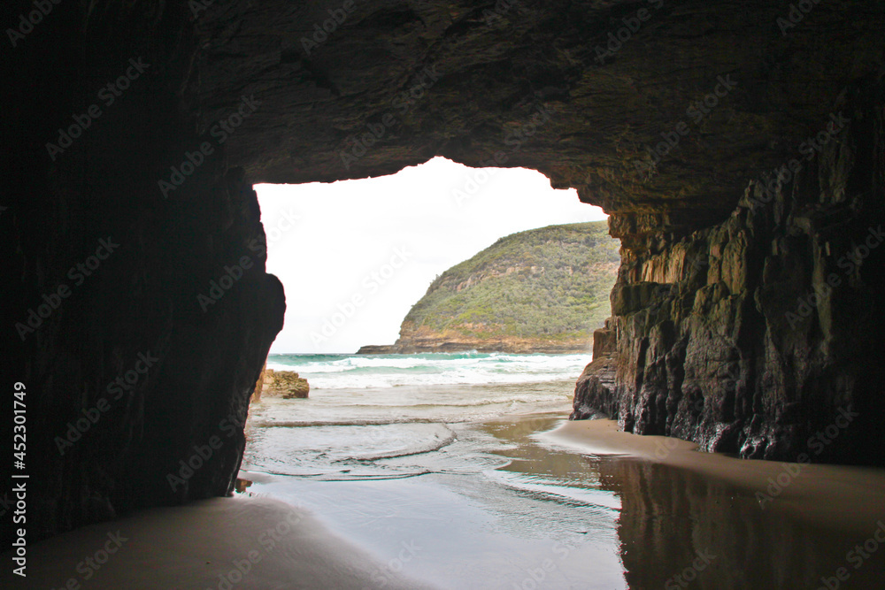 View out of the Remarkable cave to the sea. Waves washing over the sandy floor. No people.