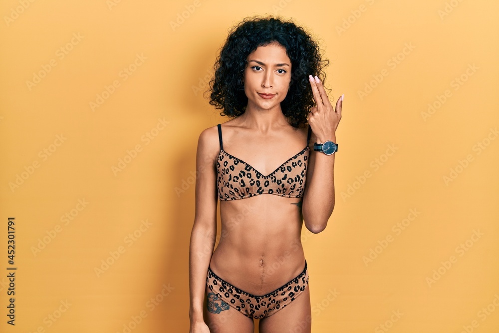 Naklejka premium Young latin girl wearing bikini shooting and killing oneself pointing hand and fingers to head like gun, suicide gesture.