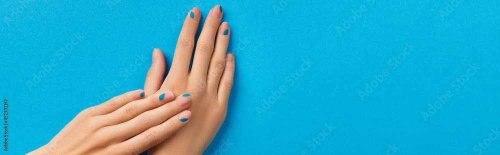 Womans hands with summer manicure on blue background Womans hands with summer manicure on blue background