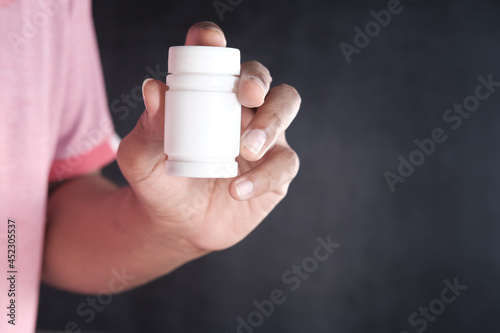 young man hand holding medicine pill container 