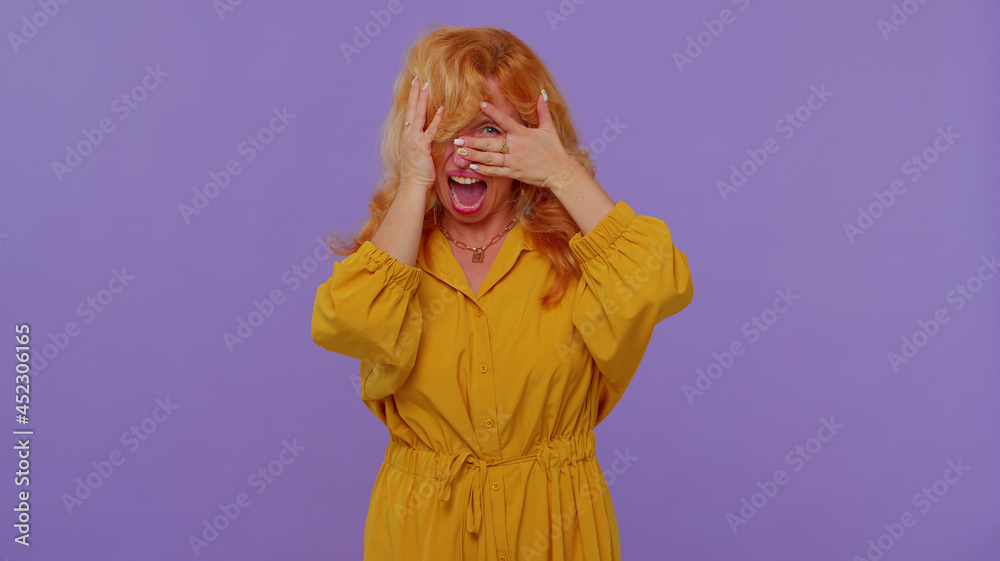 Redhead adult girl scared fearful, covering ears with hands, closing eyes, meeting her own phobia, evidence horror event, screaming, shouting at loud, freaked out. Young woman on purple background
