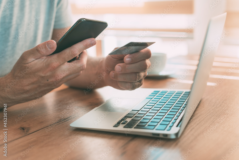 Online shopping from home, man using laptop computer, mobile smart phone and credit card to purchase Online shopping from home, man using laptop computer, mobile smart phone and credit card to purchase