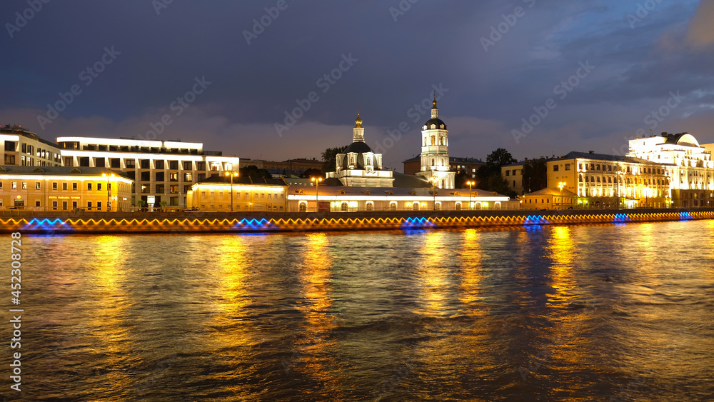 Night city view of architecture, churches and the Moskva river in Moscow, Russia. Reflection of lights in the water.