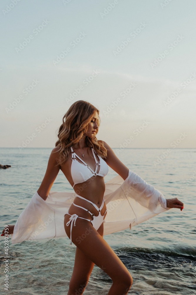 beautiful woman with blond hair in elegant bikini posing on the sunset beach - obrazy, fototapety, plakaty 
