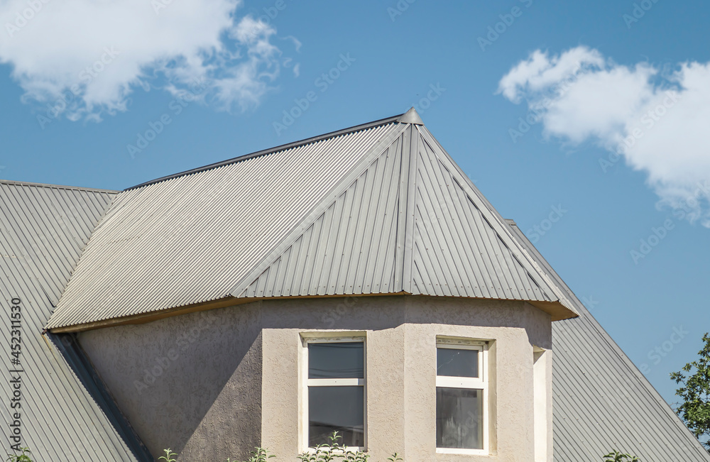 The roof of the house from a galvanized metal profile against the sky.