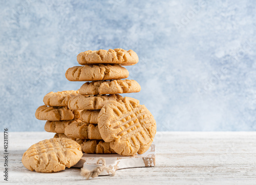 Peanut butter cookies stack on wooden cutting board. Traditional american dessert, nutrition snack, dessert or breakfast food. Blue and white background. Closeup food. Criss cross patterned biscuits. photo