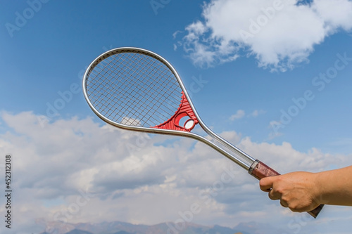 Tennis racket on the background of the sky with clouds © kvdkz