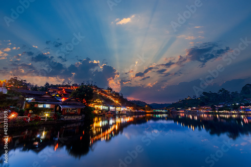 beautiful sunsets view of Ban rak thai, Mae Hong Son, Thailand. The dusk scene after sunset with the reflection of the buildings and night market on the pond.
