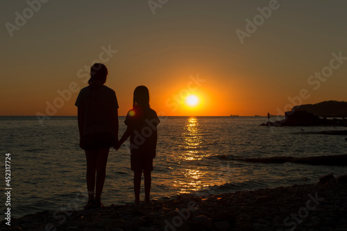 Silhouettes of children against the sunset on the seashore. The concept of family values.