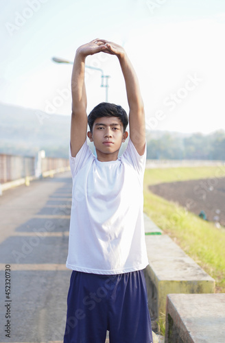 young asian man having streaching before jogging in the morning
