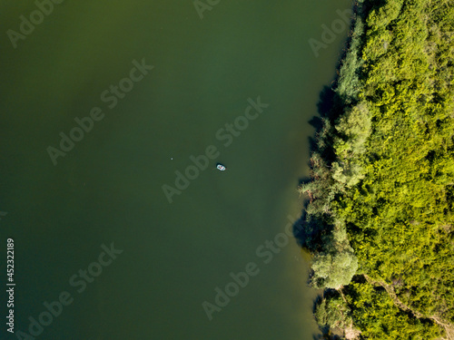 Принти на полотні Aerial view of a green lake with a boat and coastline trees