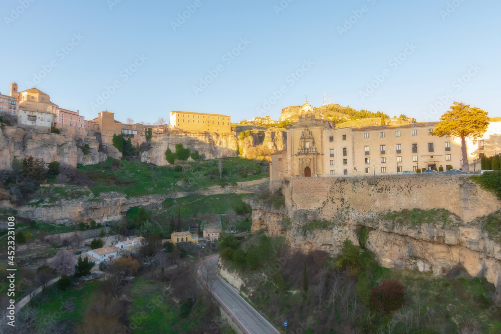 Cityscape in old city changing light at sunset; Parador nacional , former Convent of San Pablo with old town hanging over mountain in Cuenca, World Heritage Site, Spain. Horizontal view
