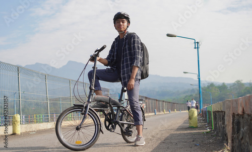 asian young man with backpack having rest after ride bicycle
