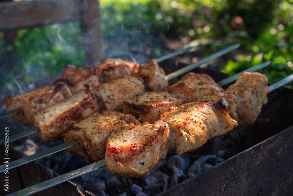 Meat on the grill. Shish kebab on fire. Preparation of meat called shashlik. Barbecue time. Picnic concept. Grilled pork with charcoal. Grilling kebab on skewer. Delicious barbeque meal.