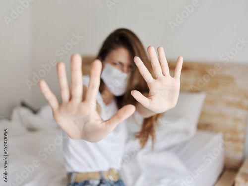 woman covered with hands from camera medical mask isolated room bed pillows quarantine
