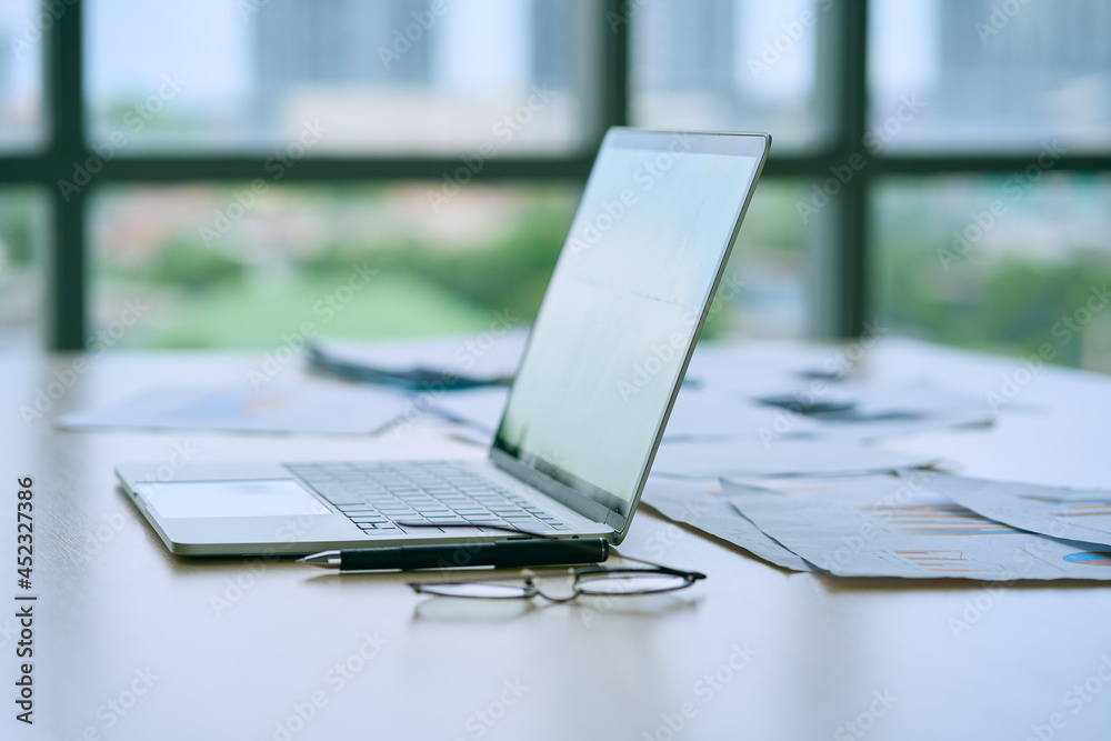 Fototapeta premium Business laptop and glassware and stationery and paper of chart on table office