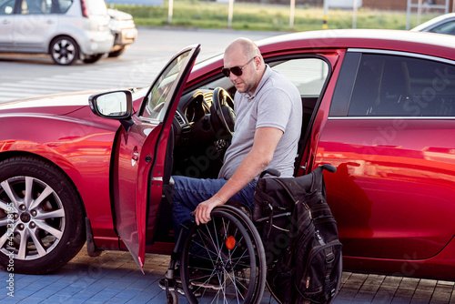 Young handicapped driver getting in red car fom wheelchair © romaset